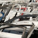 A variety of car doors in different colors arranged in a junkyard setting. - Photo by Aziz Er on Pexels