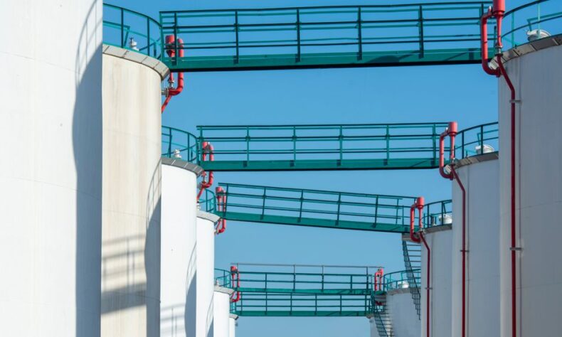 Modern industrial storage tanks with walkways against a clear blue sky. - Photo by Jan van der Wolf on Pexels