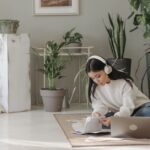 Asian woman seated on floor, using laptop and headphones, surrounded by indoor plants. - Photo by Pavel Danilyuk on Pexels